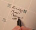 Close-up of a hand writing podcast recording date on a calendar. Ideal for content planning concepts.