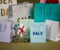 A mix of colorful shopping bags and a small cart displaying a discount gift.